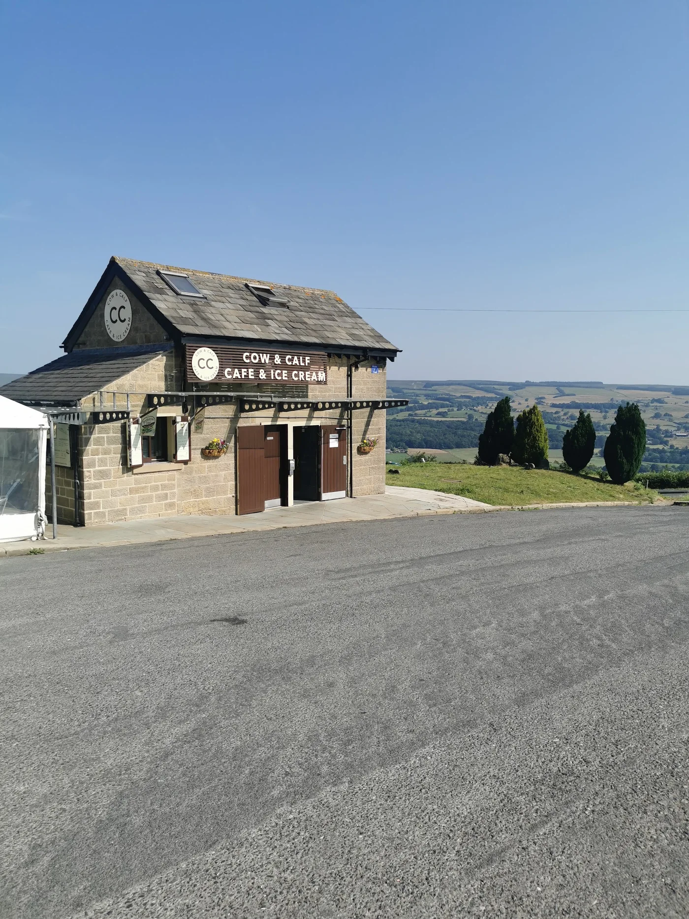The stone Cow & Calf Rock Cafe building and its CC sign, looking out over the valley