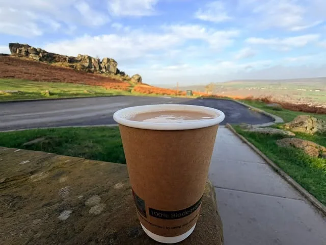 A takeaway coffee on a stone wall with the moor behind it
